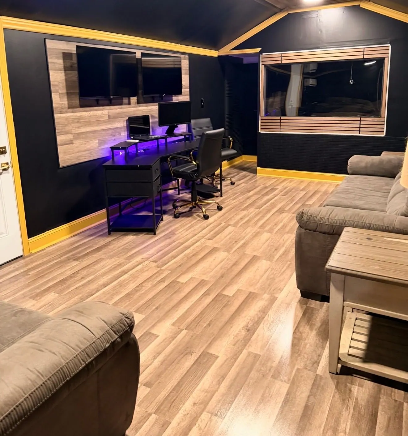 Control room at Game Time Studios with gold-trimmed acoustic walls, monitors, and a sofa